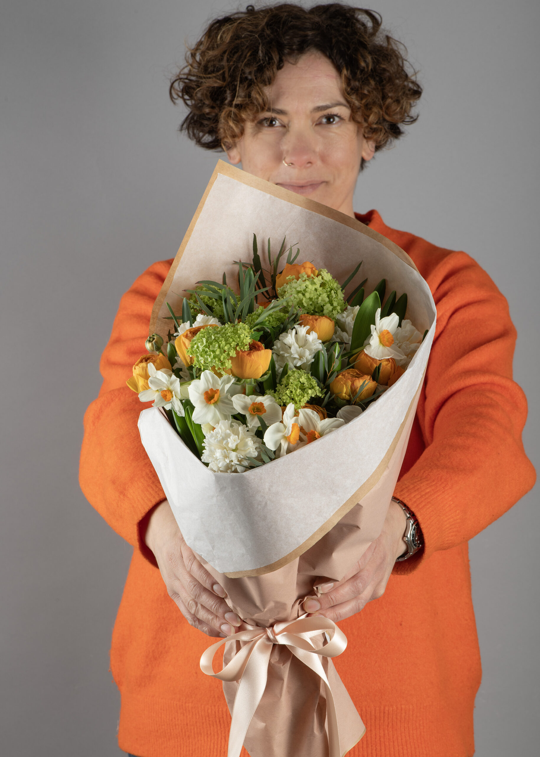 Georgina-holding-a-Spring-bunch-in-orange-creams-and-greens